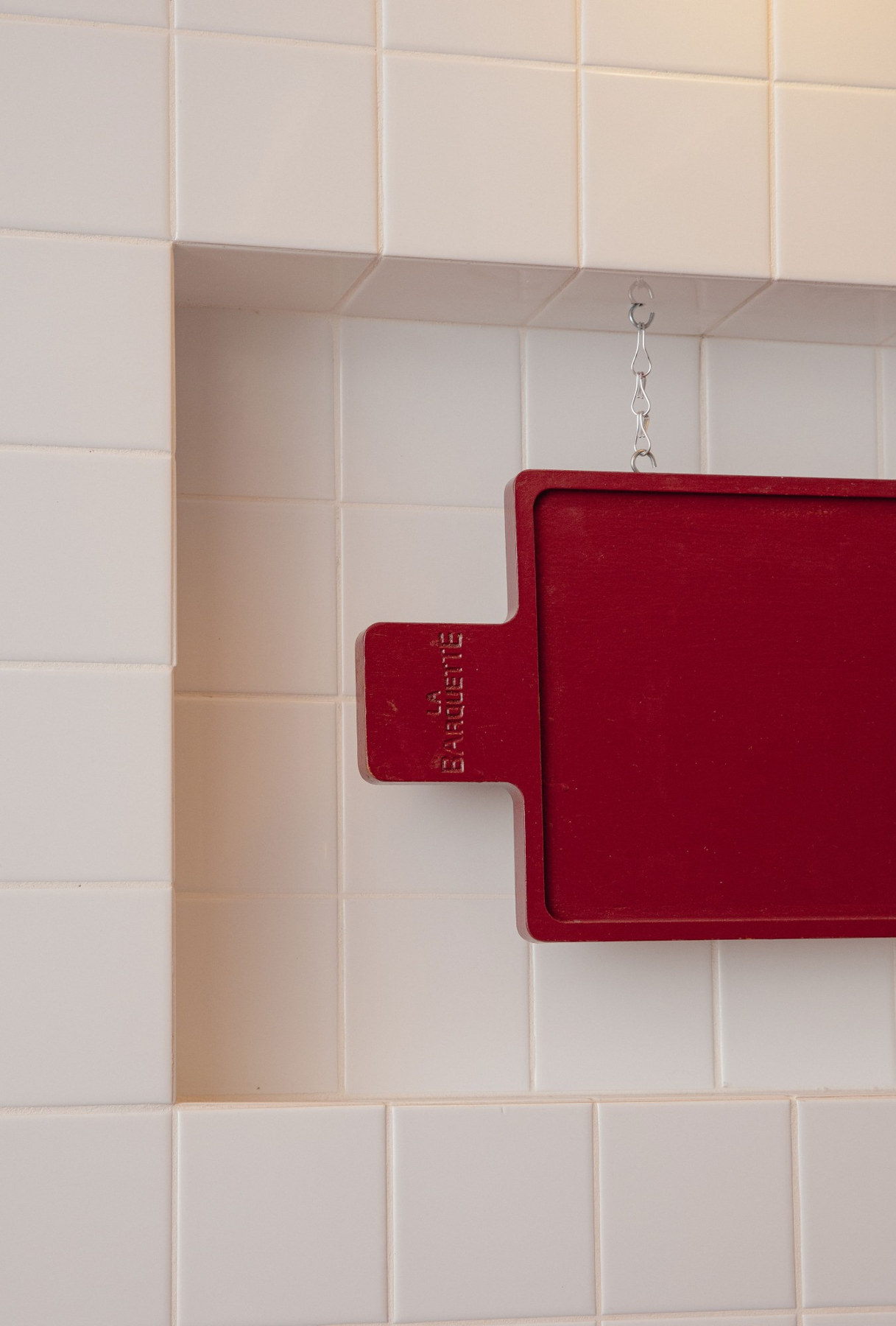 Tabla roja de La Barquette colgada en la pared de azulejo